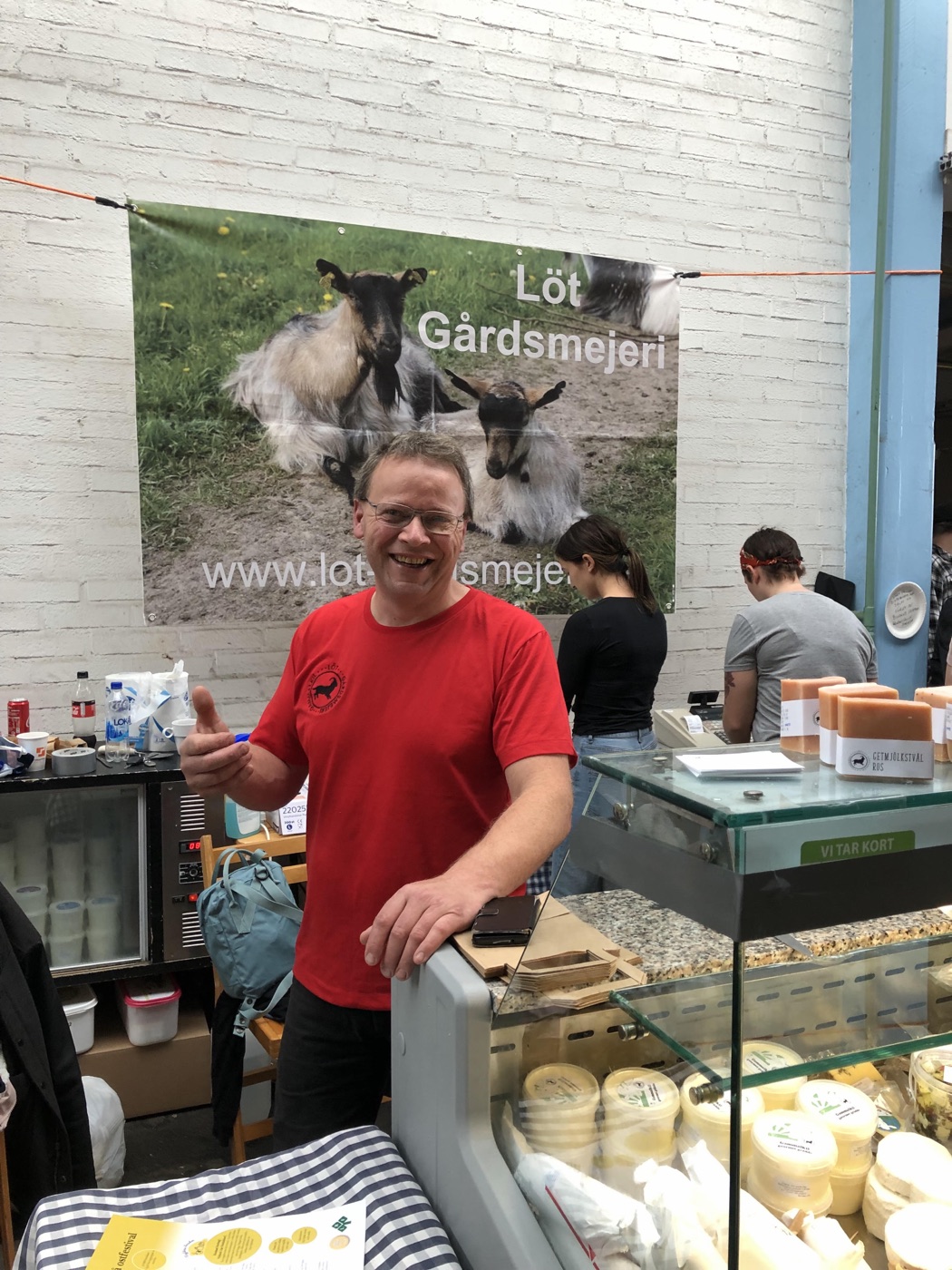 Terje Erik står vid marknadsdisken framför en banderoll för Löt Gårdsmejeri
